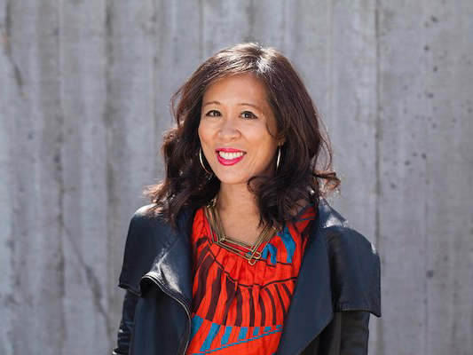 Photo of the author Lisa Ko, an East Asian woman with long-ish black hair. She is wearing a red shirt and black leather jacket and earrings.