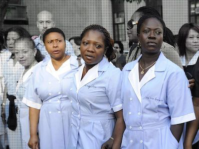Photo illustration of several people standing outside. Three of them in the front of black and in color (the other people are in black and white.) The three in color are wearing blue maid uniforms.