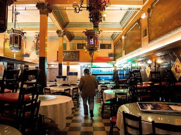 A man with his back to the camera walks through an empty restaurant, the Far East Cafe