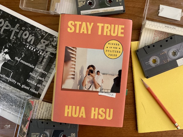 A book, Stay True by Hua Hsu, among mix tapes, a notebook, and a zine.
