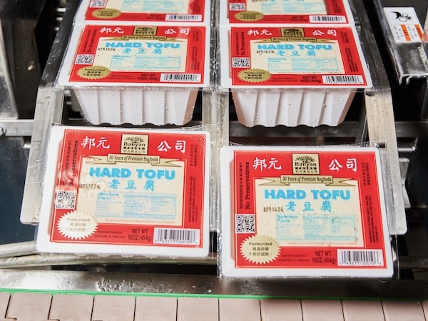 Packages of Banyan brand tofu coming off an assembly line in a factory.