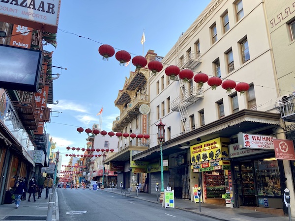 Grant street in SF Chinatown, empty of cars, with some storefront cloes, and red laterns strung across the street.
